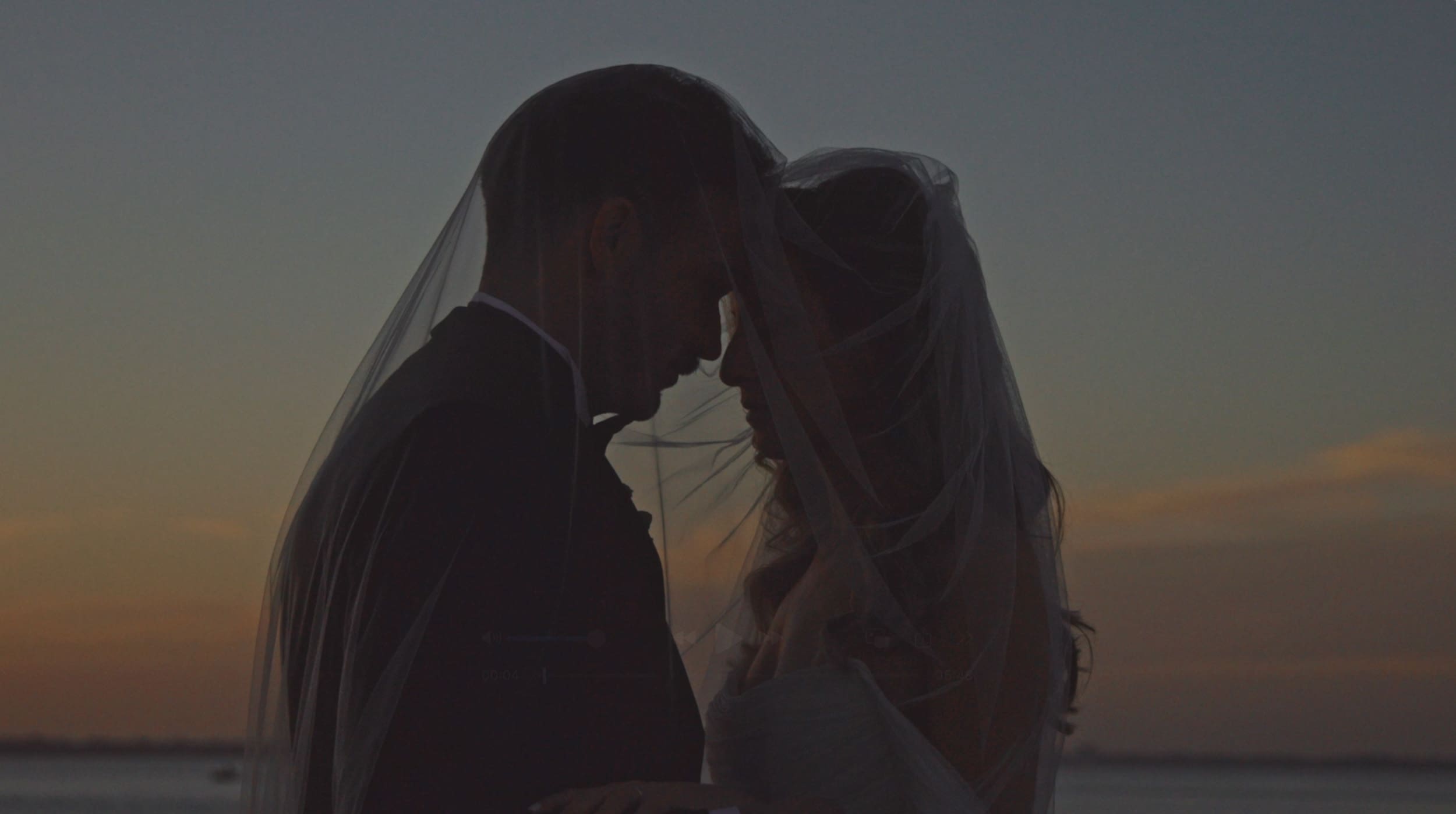 man and women in wedding attire with foreheads lightly pressed together